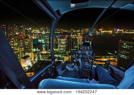 Helicopter flying over Tokyo cityscape, the Bay area with its bridges and Odaiba by night from Tokyo skyline in Japan.