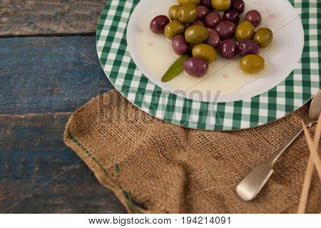 High angle view of olives served in plate on wooden table