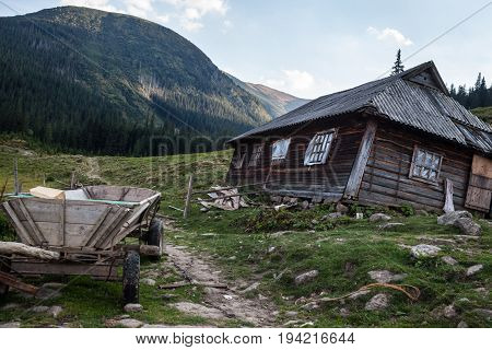 Wooden shepherds' house in the Ukrainian Carpathians with wooden cart nearby.