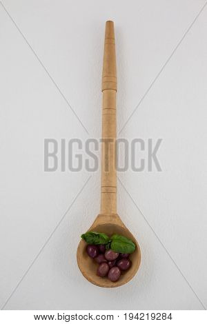 Overhead view of brown olives with herb in woden laddle on ladle