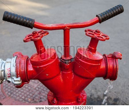 Red fire hydrant with connected hose. Close-up.