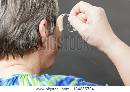 Closeup senior woman with hearing aid in her ear. Health care hear amplify device for the deaf.