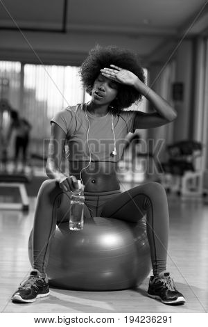 happy african american woman with a curly afro hairstyle in a  gym relaxing after pilates workout