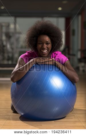 happy african american woman with a curly afro hairstyle in a  gym relaxing after pilates workout