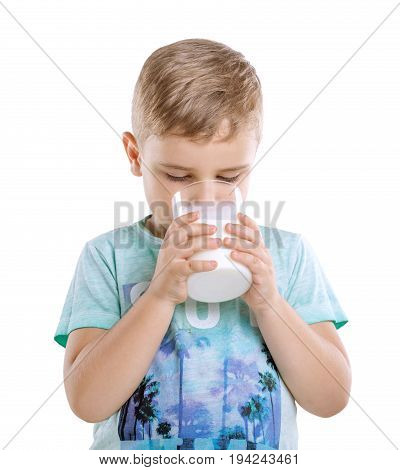 Cute adorable little boy is holding a glass full of milk and drinking fresh milk isolated on a white background. Charming small kid is drinking organic milk from a glass.