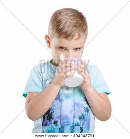 Adorable little kid is holding a glass of organic milk and drinking fresh milk isolated on awhite background. Close-up portrait of a cute little boy in a blue t-shirt with a full glass of milk.