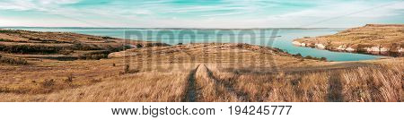 Scenic sea view from top of hills. Beautiful summer background. Amazing landscape with yellow meadows green trees blue sky steep cliffs and picturesque bay. Panoramic photo. Camping rest relax.