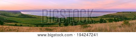 Scenic sea view from top of hills. Beautiful summer background. Amazing landscape with yellow meadows green trees blue sky steep cliffs and picturesque bay. Panoramic photo. Camping and rest.