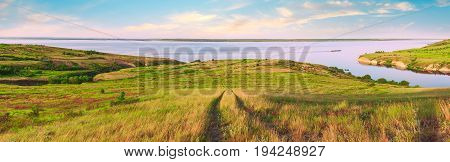 Scenic sea view from top of hills. Beautiful summer background. Amazing landscape with yellow meadows green trees blue sky steep cliffs and picturesque bay. Panoramic photo. Camping rest relax.