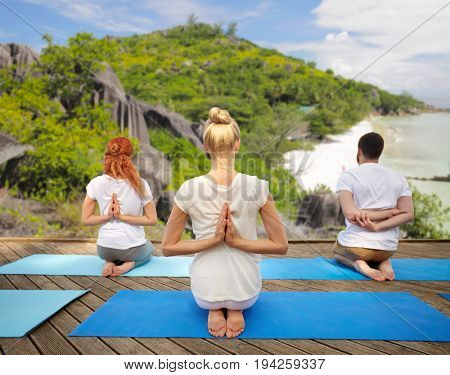 fitness, sport, yoga and healthy lifestyle concept - group of people exercising in reverse prayer pose over tropical beach background