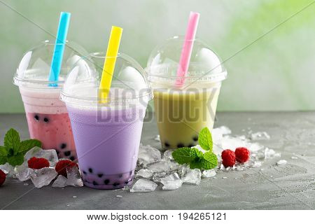 Variety of bubble tea in plastic cups with thick straws