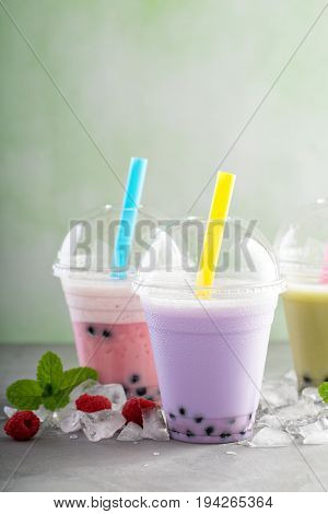 Variety of bubble tea in plastic cups with thick straws