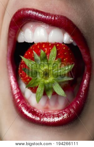 Woman has red strawberry in her mouth