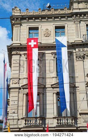 ZURICH - AUGUST 1: Swiss National Day parade on August 1, 2016 in Zurich, Switzerland. Facade of Credit Suisse building decorated with national flag and flags of cantons