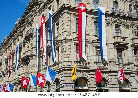 ZURICH - AUGUST 1: Swiss National Day parade on August 1, 2016 in Zurich, Switzerland. Facade of Credit Suisse building decorated with national flag and flags of cantons