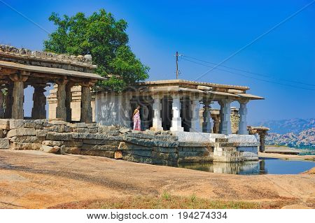 Hampi, India - November 19, 2012: Indian woman in traditional clothes stands at the ancient ruins of Hemakuta hill in Hampi, Karnataka, India. UNESCO World Heritage Site
