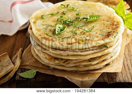 Stack of fried green onion pancakes on a wooden board