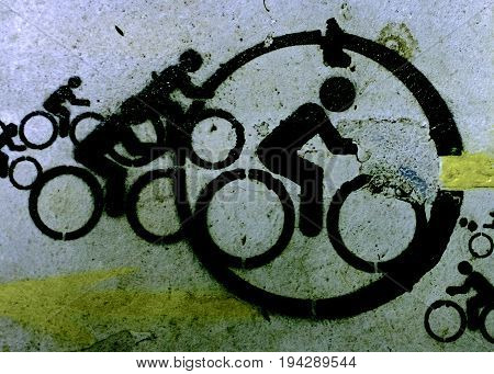 Group of different sized black cycling icons of a person on a bicycle painted on an old grunge urban wall in a close up view