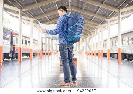 man traveler with backpacker look searching location at trainstation travel concept