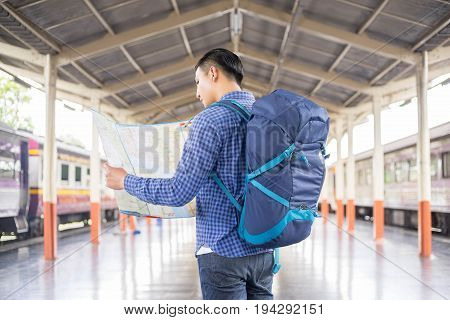 man traveler with backpacker look searching location at trainstation travel concept