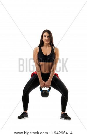 A female fitness model makes a squat with weights on the buttocks on a white isolated background the position of the half-breed