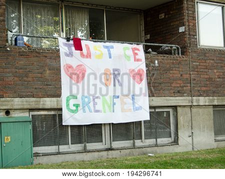 LONDON, UK - JULY 5, 2017:  Hand drawn banner calling for Justice for Grenfell displayed on the balcony of a flat next to the Grenfell Tower block in which at least 80 people were killed in a fire Kensington London.