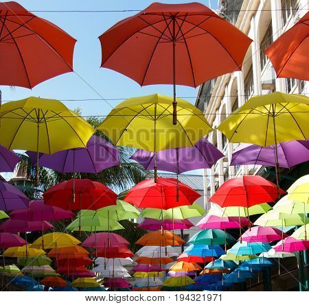 Group of multicolored umbrellas decorating a street by the top of it