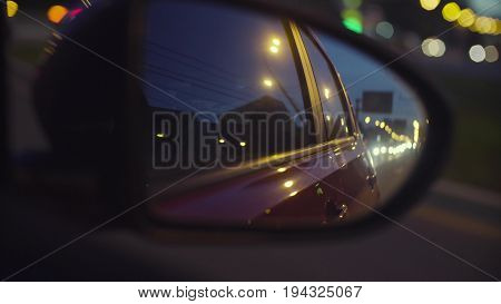 Point of View of the city traffic in car's rearview mirror and side window. Defocused city lights. Moscow, june, POV