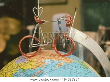 Miniature Bicycle Figure on Geography Globe or Planet Sphere Model Cyling to Destination.