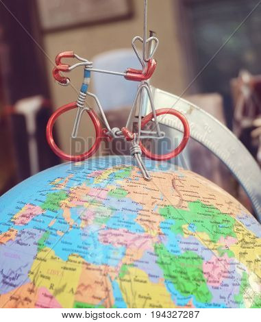 Miniature Bicycle Figure on Geography Globe or Planet Sphere Model Cyling to Destination.