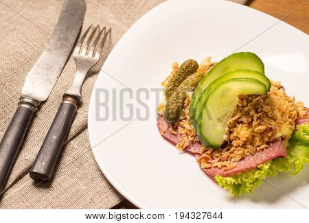 Danish specialties and national dishes high-quality open sandwich. Salami with crispy onion remoulade and cucumber served on a plate ready for eating