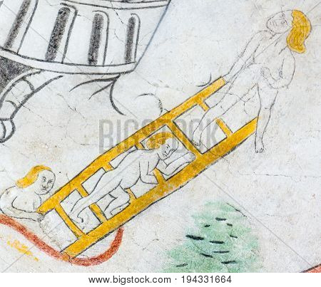 Mortals cimbing on a laldder medieval gothic fresco in Vinderslev church Denmark June 22 2017