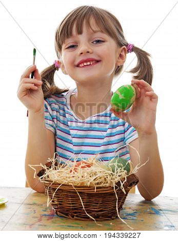a happy little girl painting easter eggs