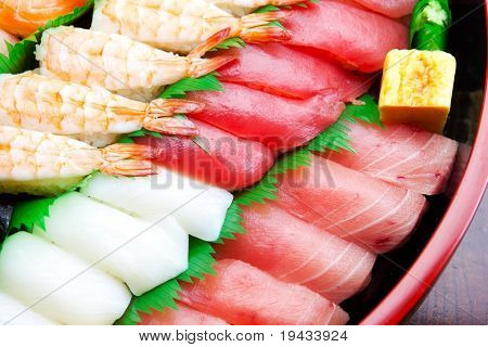 Sushi dispuesto en una bandeja de sushi tradicional, colocado sobre una mesa de madera. Aislado en blanco.