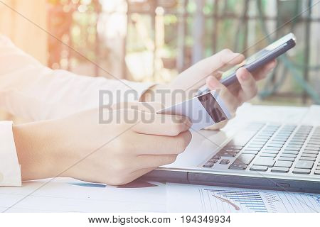 Woman's Hands Holding A Credit Card And Using Smart Phone For Online Shopping.vintage Tone