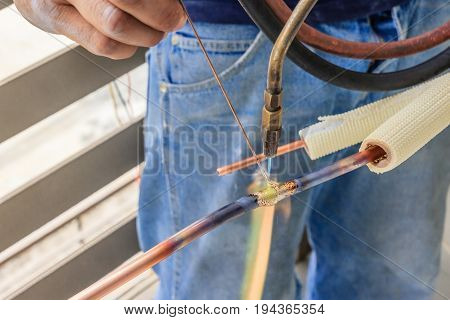Hand of Worker welds copper tube oxyfuel gas welding repair air-condition