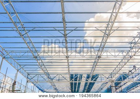 Structure of steel roof frame for building construction on blue sky background.