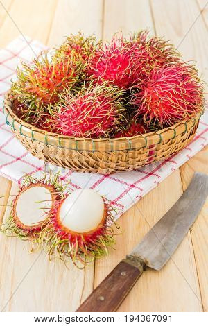 fresh tropical rambutan fruits over basket with knife on wood background fruit in Thailand