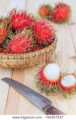 fresh tropical rambutan fruits over basket with knife on wood background fruit in Thailand