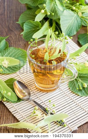 Lime flower tea in glass cup with linden flowers. midicinal remedy.