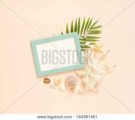 Empty frame and marine items on creme background. Starfish and seashells. Selective focus. Place for text. Flat lay top view.
