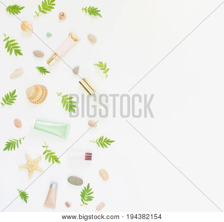 Cosmetics background. Cosmetics SPA makeup tubes, bottles, sea pebbles and shells on white background. Flat lay, top view.