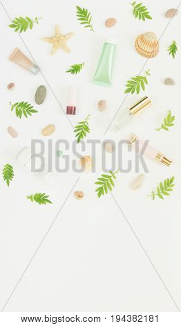 Cosmetics background. Cosmetics SPA makeup tubes, bottles, sea pebbles and shells on white background. Flat lay, top view.