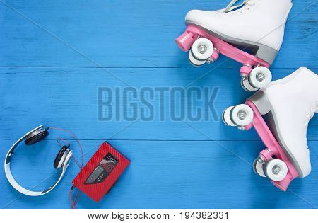 Sport, healthy lifestyle, roller skating background. White roller skates, headphones and vintage tape player. Flat lay, top view.