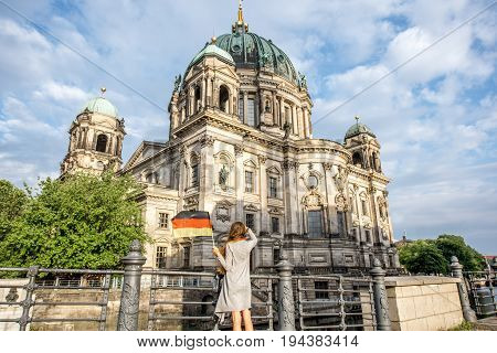 Young woman tourist standing back with german flag near the famous cathedral in Berlin city