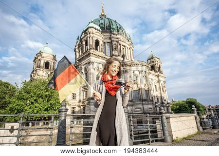 Young and happy woman tourist with photo camera in front of the famous cathedral in Berlin city