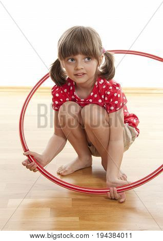 little girl doing fitness exercise with a red hoop