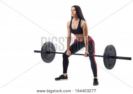 Young athletic brunette woman doing squat with a barbell on white isolated background side view legs stand wide in a half-bent position close-up