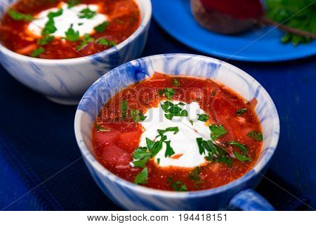 Ukrainian Traditional Borsch. Russian Vegetarian Red Soup  In Blue Bowl On Blue Wooden Background.