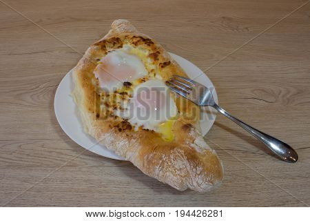 Adjarian Khachapuri - georgian cheese pie with egg. Adjarian khachapuri on a on a plate. Open pie with cheese in the shape of the boat